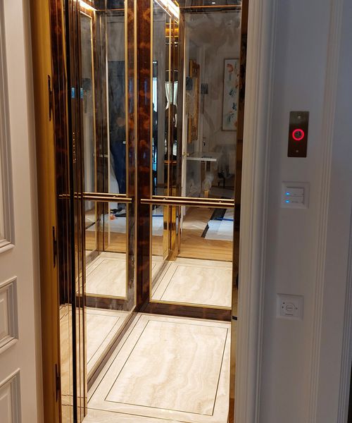 Elegante ascensore con parete frontale, porte e colonna comandi rivestite in acciaio inox colore oro